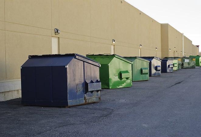 a construction worker moves construction materials near a dumpster in Commerce